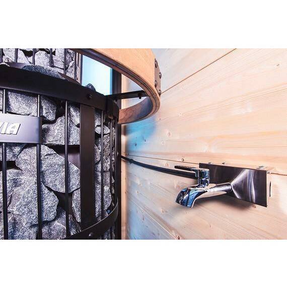 Harvia WP250TH Sauna Water Heater for Thermio Stoves, stone-caged unit mounted on wood paneling beside a chrome tap fixture.
