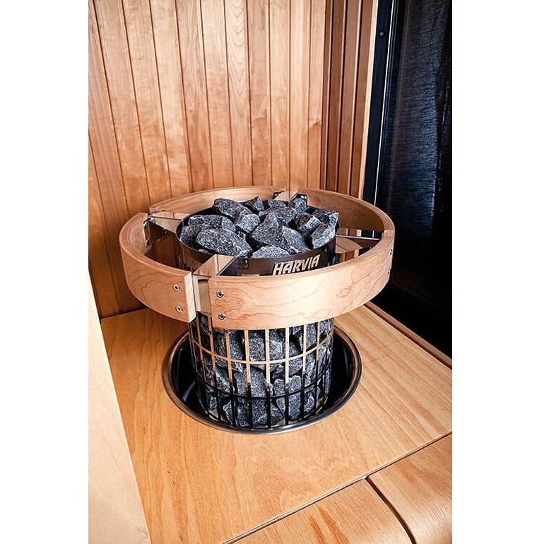 Harvia Cilindro Safety Railing for 11kW Sauna Heaters, installed around a heater topped with stones inside a wood paneled sauna