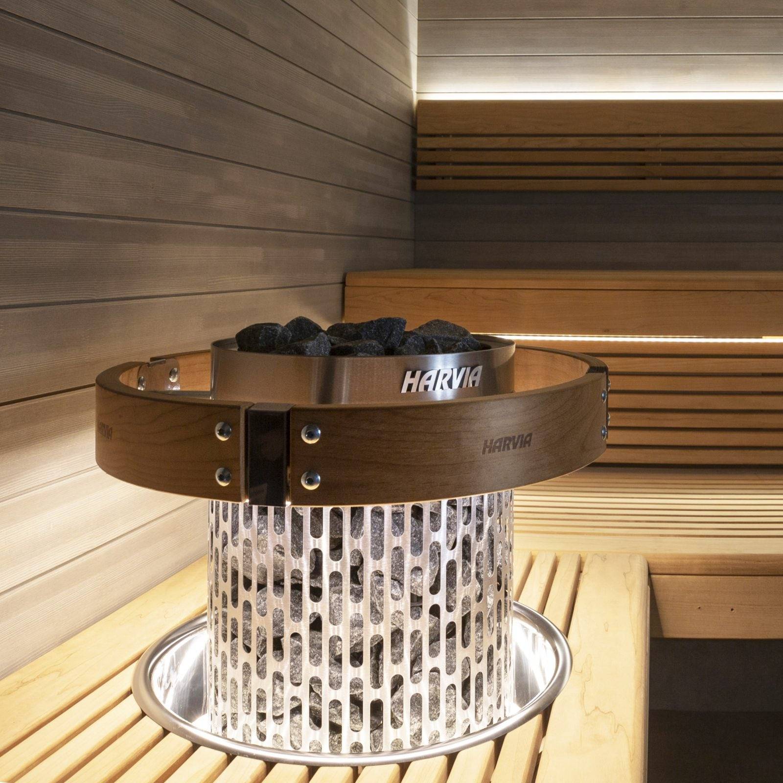Harvia Cilindro LED Safety Railing for 6 & 8kW Sauna Heaters, close up on the Harvia branded ring lit around a stone filled heater in a sauna corner.