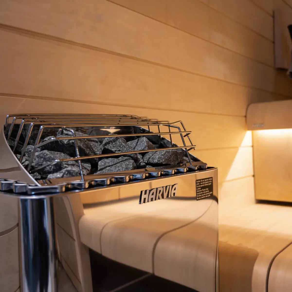 Harvia KIP60B 6kW Electric Sauna Heater with Built-In Controls, close up side angle of dark stones and the Harvia logo.