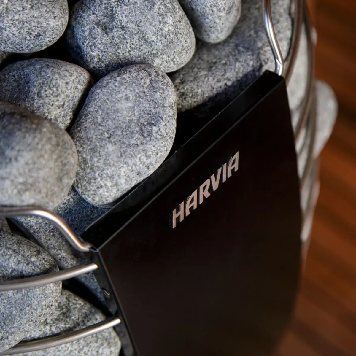 Harvia Spirit SP60E 6kW Electric Sauna Heater, close up of the black panel with the Harvia logo nestled among the sauna stones.