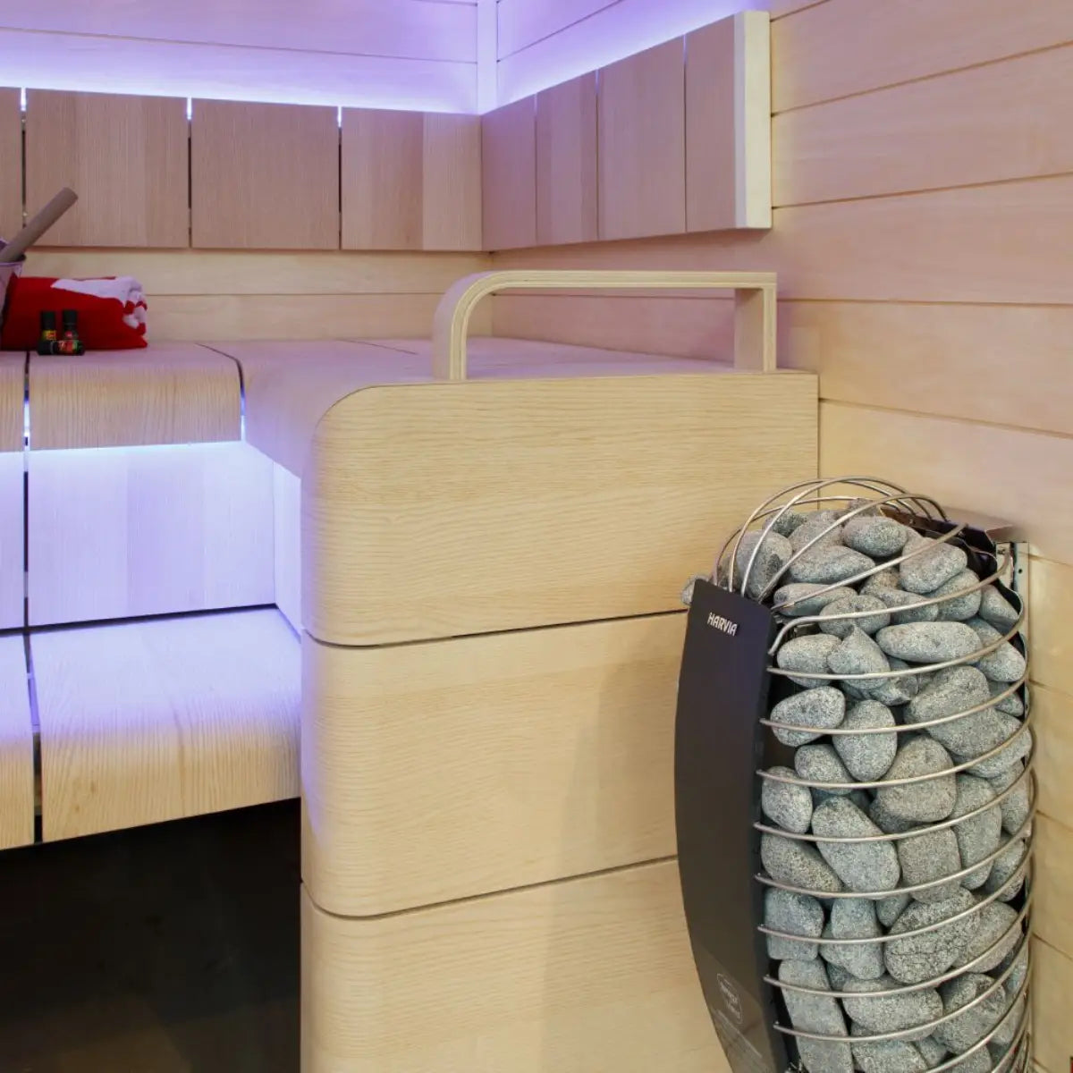 Harvia Spirit SP80E 8kW Electric Sauna Heater in a modern sauna interior with wood benches and purple LED lighting.