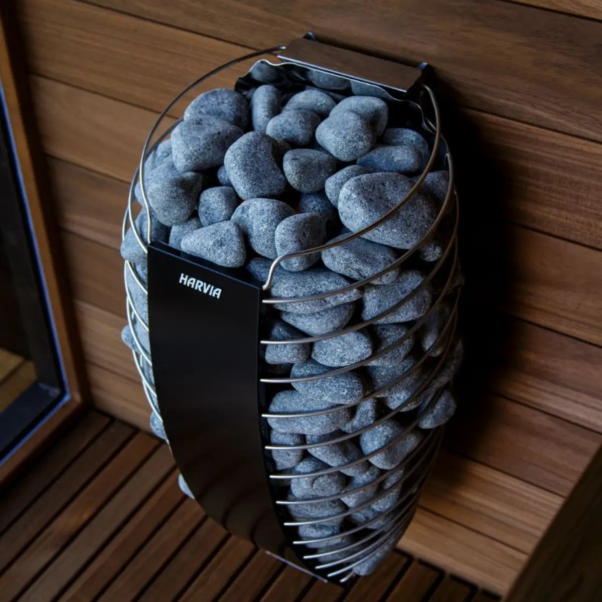 Harvia Spirit SP90E 9kW Electric Sauna Heater mounted on a wood paneled sauna wall, angled view showing the stone basket.