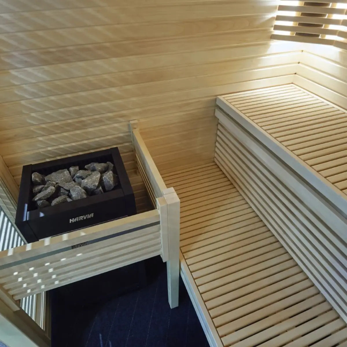 Harvia Virta HL90 9kW Electric Sauna Heater, overhead view of the unit topped with stones inside a wood paneled sauna corner.