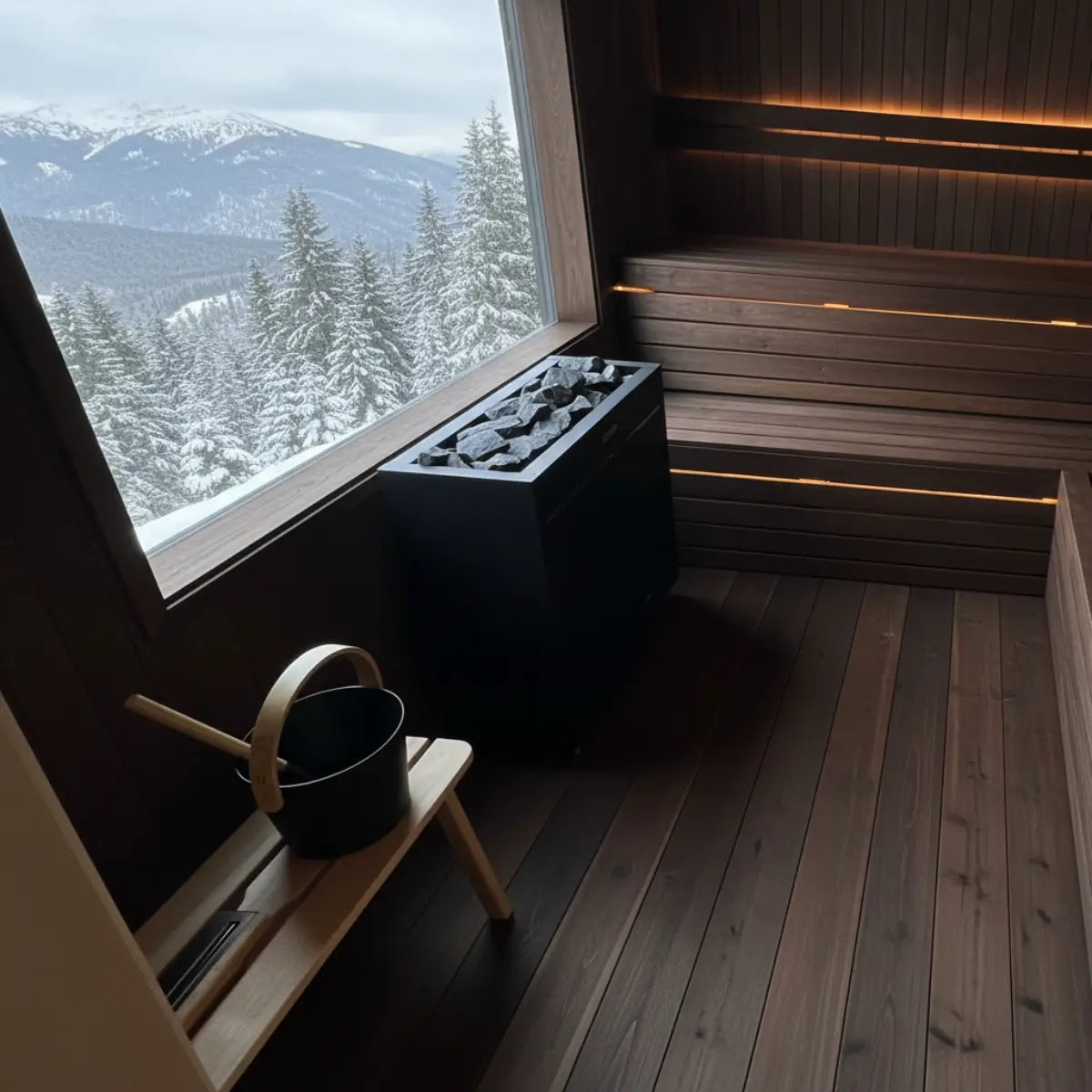 Harvia Virta Pro HL200 20kW Electric Sauna Heater installed in a sauna with a picture window overlooking snowy mountains and pine trees.