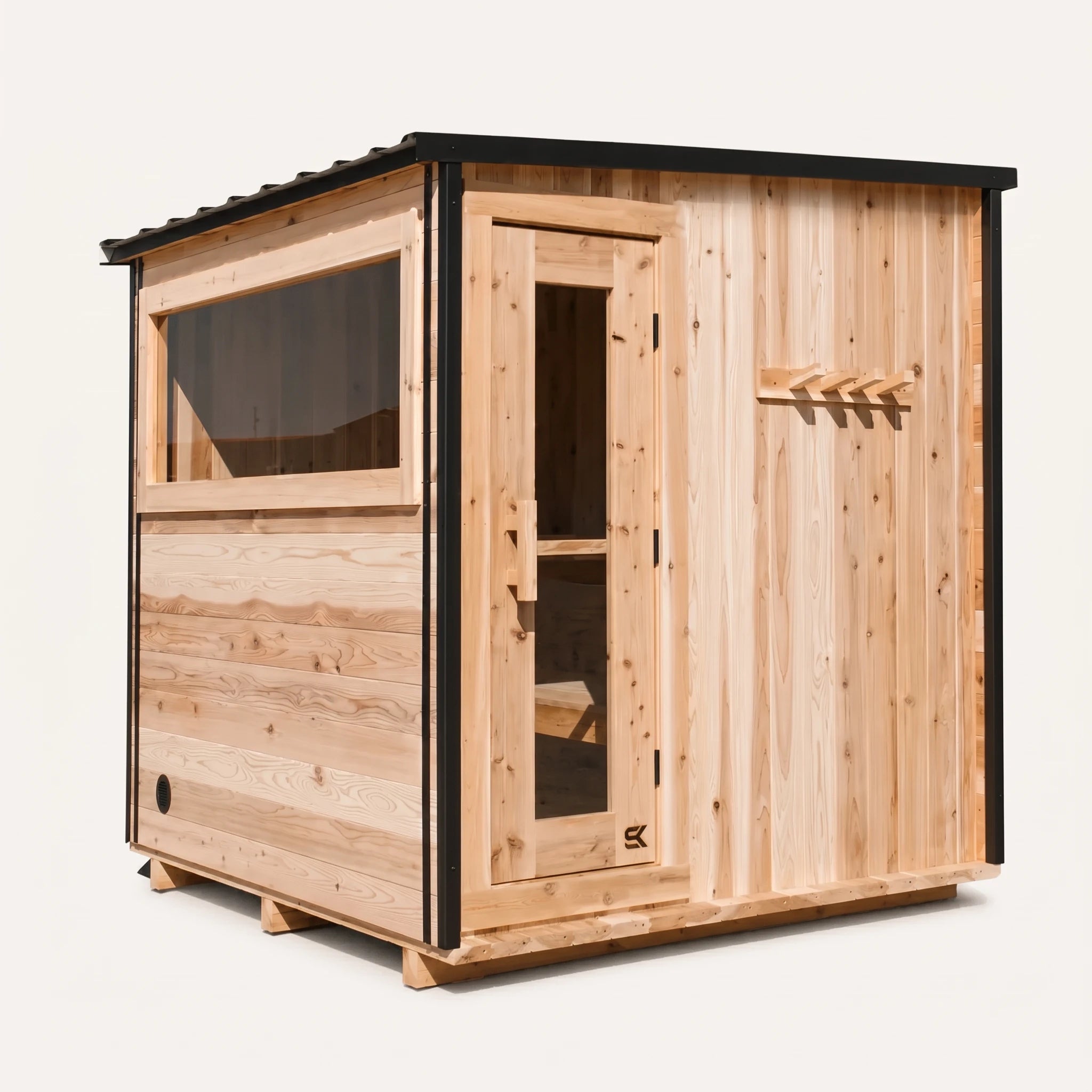 The Summit cedar 4-6 person outdoor sauna three-quarter angle on white background showing slanted black-trim metal roof, glass door, side window, and exterior cedar peg rack.