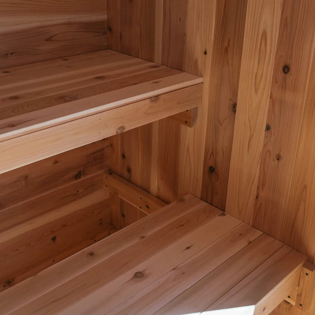 Interior view of The Summit cedar sauna showing two-tier cedar bench with sunlight streaming in from the side picture window.