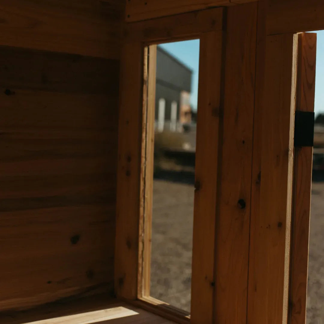 Looking outward through the open cedar door of The Sweat Cabin Deluxe sauna at the manufacturing yard.