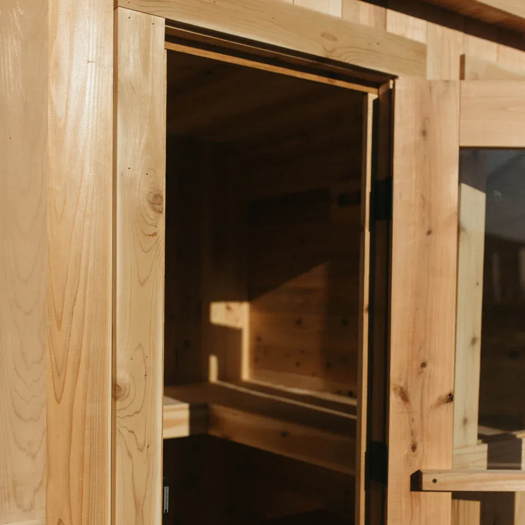 Close-up looking through the open glass door of The Sweat Cabin Deluxe showing the cedar interior bench and rear vent.