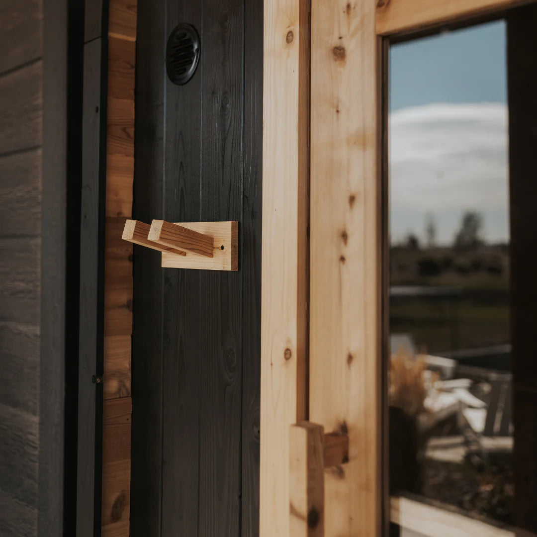 Close-up of cedar towel hook and round vent on the charred cedar exterior of The Sweat Pod Black Edition with door open.