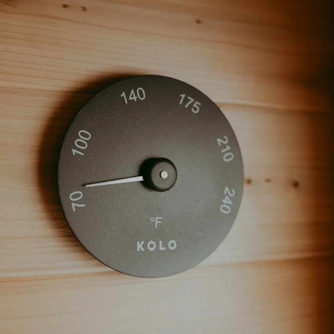 KOLO black sauna thermometer with Fahrenheit dial mounted on the cedar wall inside The Sweat Pod.