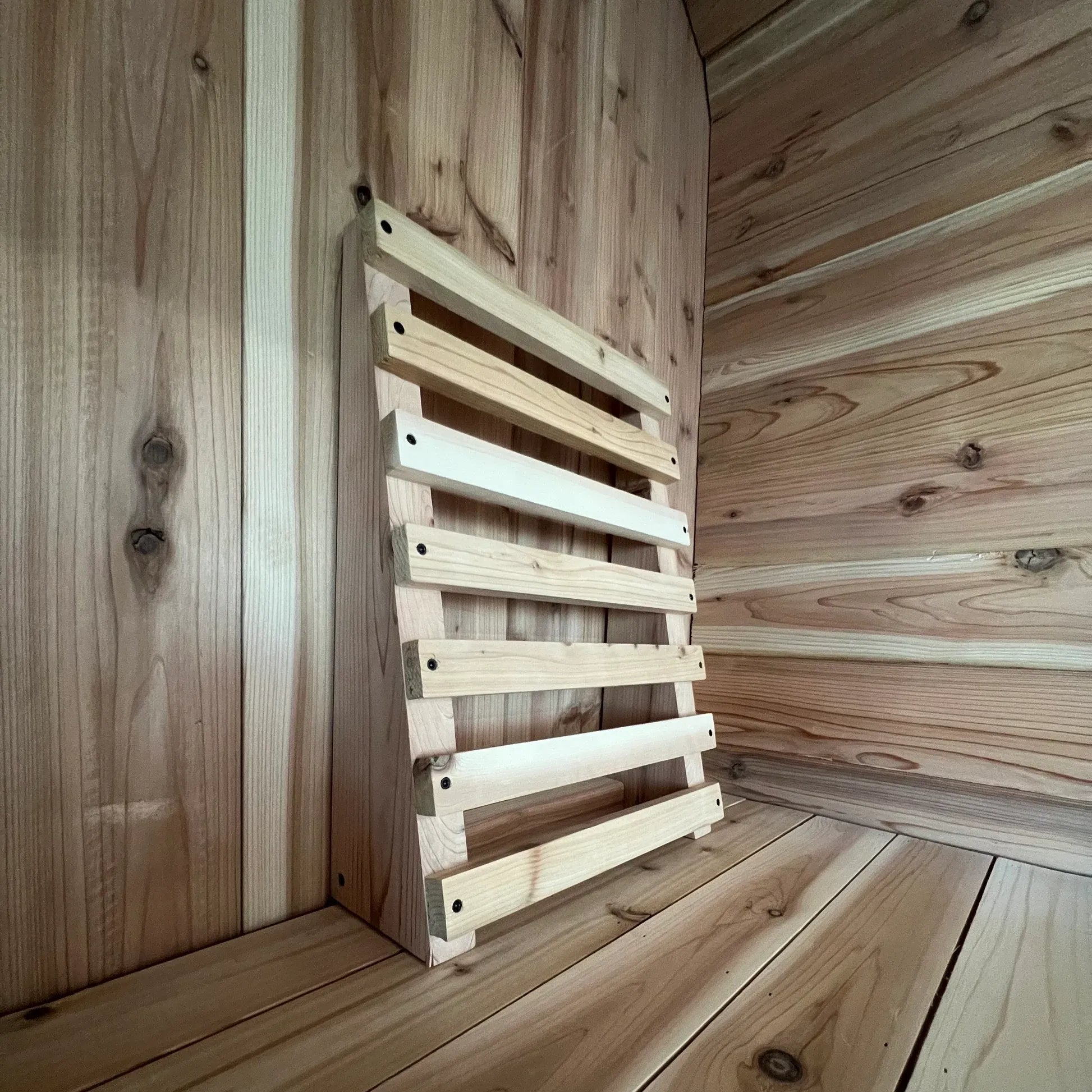Close-up of handcrafted cedar sauna backrest with contoured slats on a sauna bench