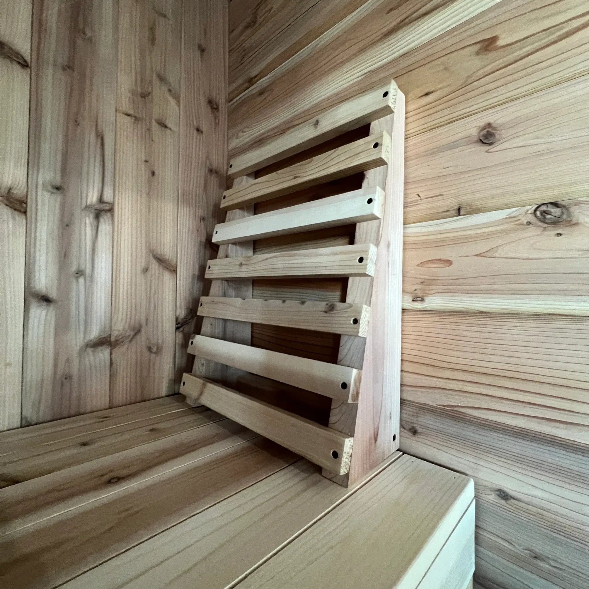 Angled side view of ergonomic cedar sauna backrest inside a wood sauna interior