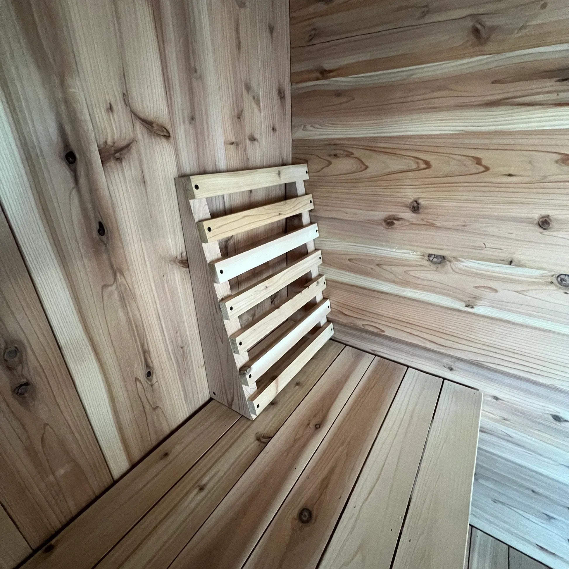 Handcrafted cedar sauna backrest positioned in the corner of a natural wood sauna