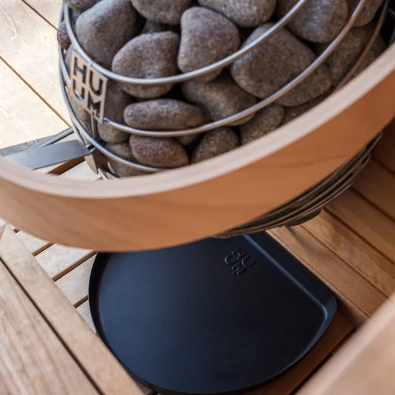 HUUM DROP electric sauna heater with black drip tray installed below the stone basket