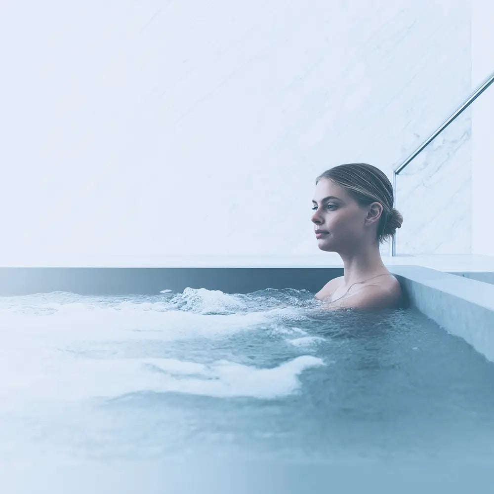 Person relaxing in an indoor cold plunge tub during a home recovery session.