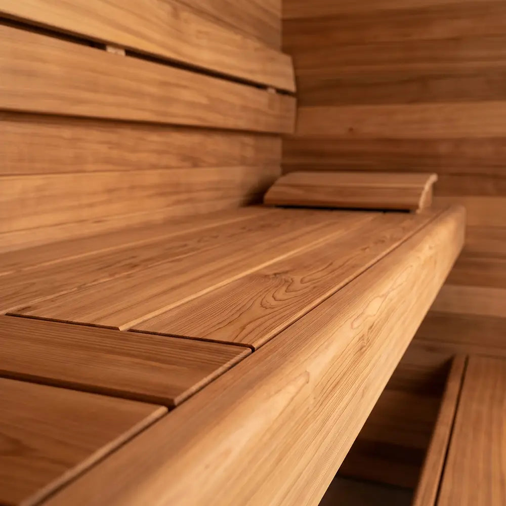 Interior view of a sauna with wooden benches and a headrest, highlighting the smooth wood surface, warm lighting, and clean, minimal design.