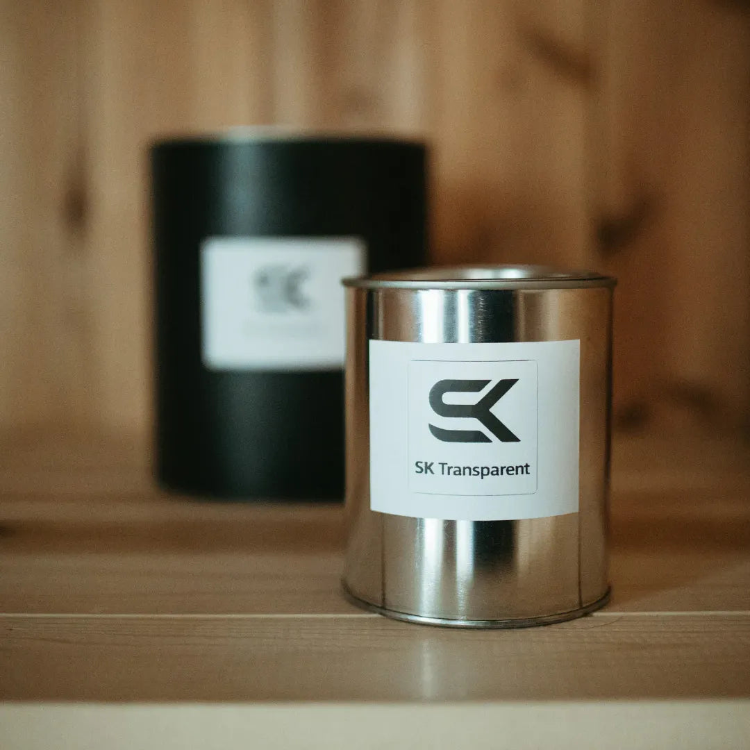 SK Clear transparent sauna stain quart can displayed on a wood sauna bench with SK Black can behind