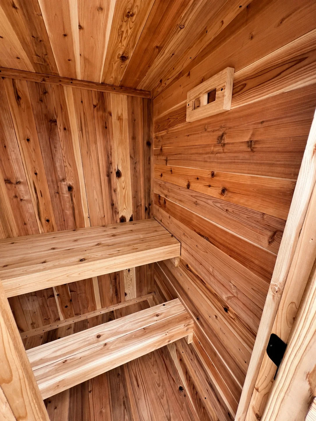 Wood bench, lower footrest, and adjustable wall vent inside the Sweat Kingdom Ridge sauna.