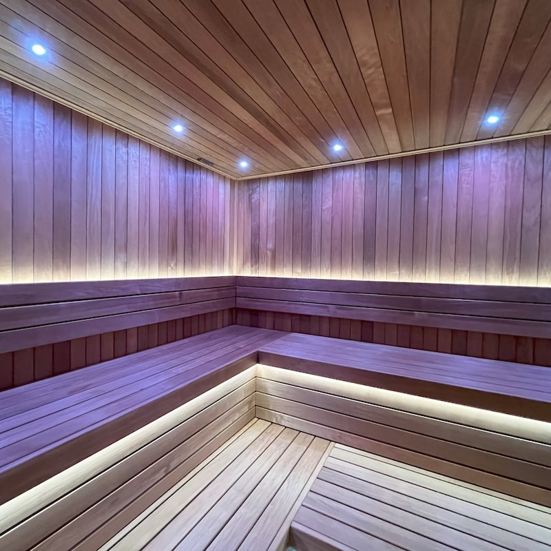 Warm white LED lighting installed under benches and in the ceiling of a wood sauna